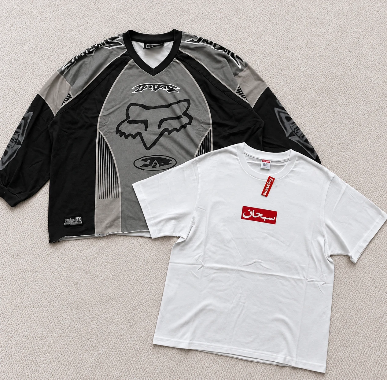Grey-and-black racing-style long-sleeve top beside a white T-shirt with a red script logo.