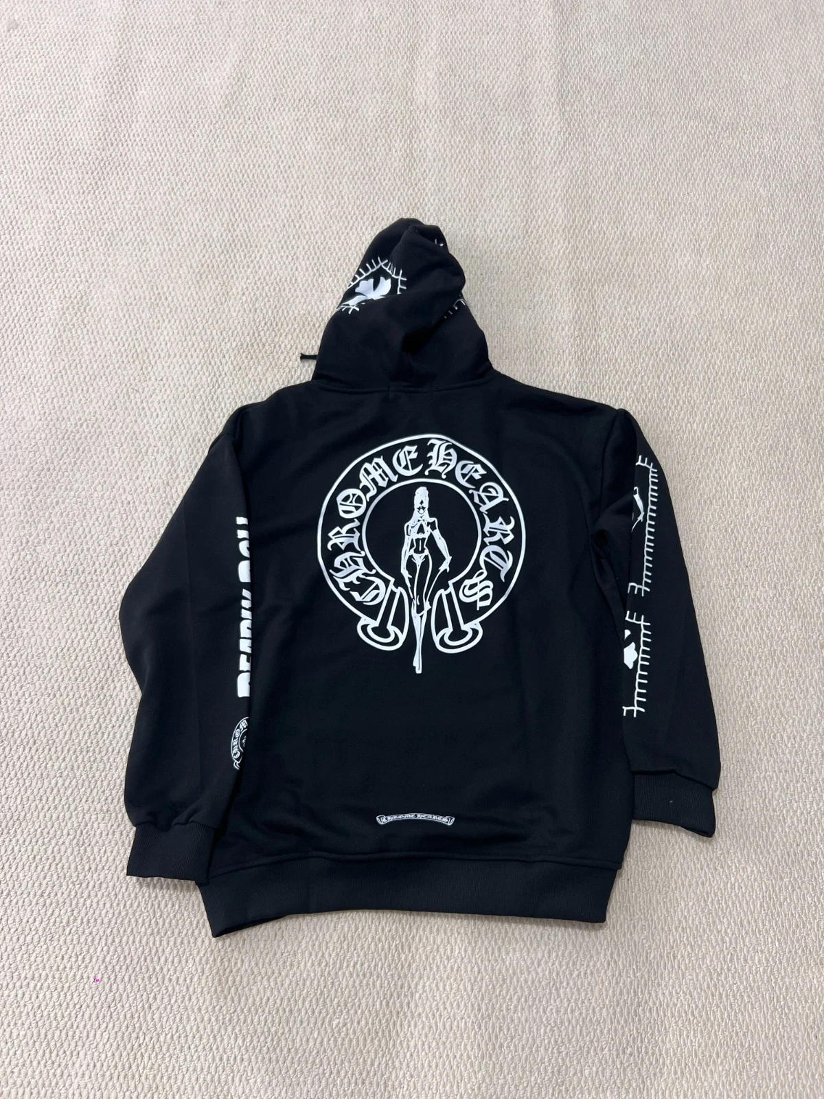 Back view of a black hoodie with a large circular cross graphic.