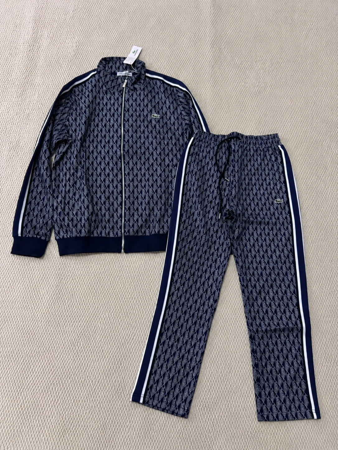 Navy patterned zip jacket and matching trousers laid flat together.