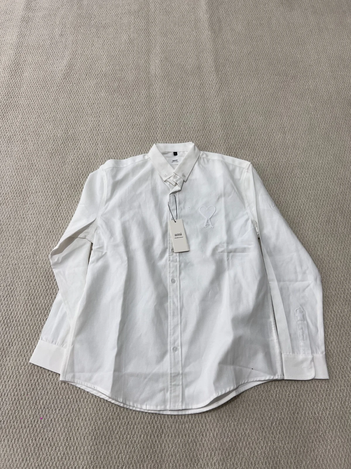 White long-sleeve button-front shirt with a small chest emblem.