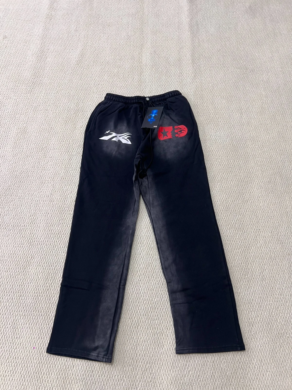Wide black trousers with red and white graphics around the upper front.
